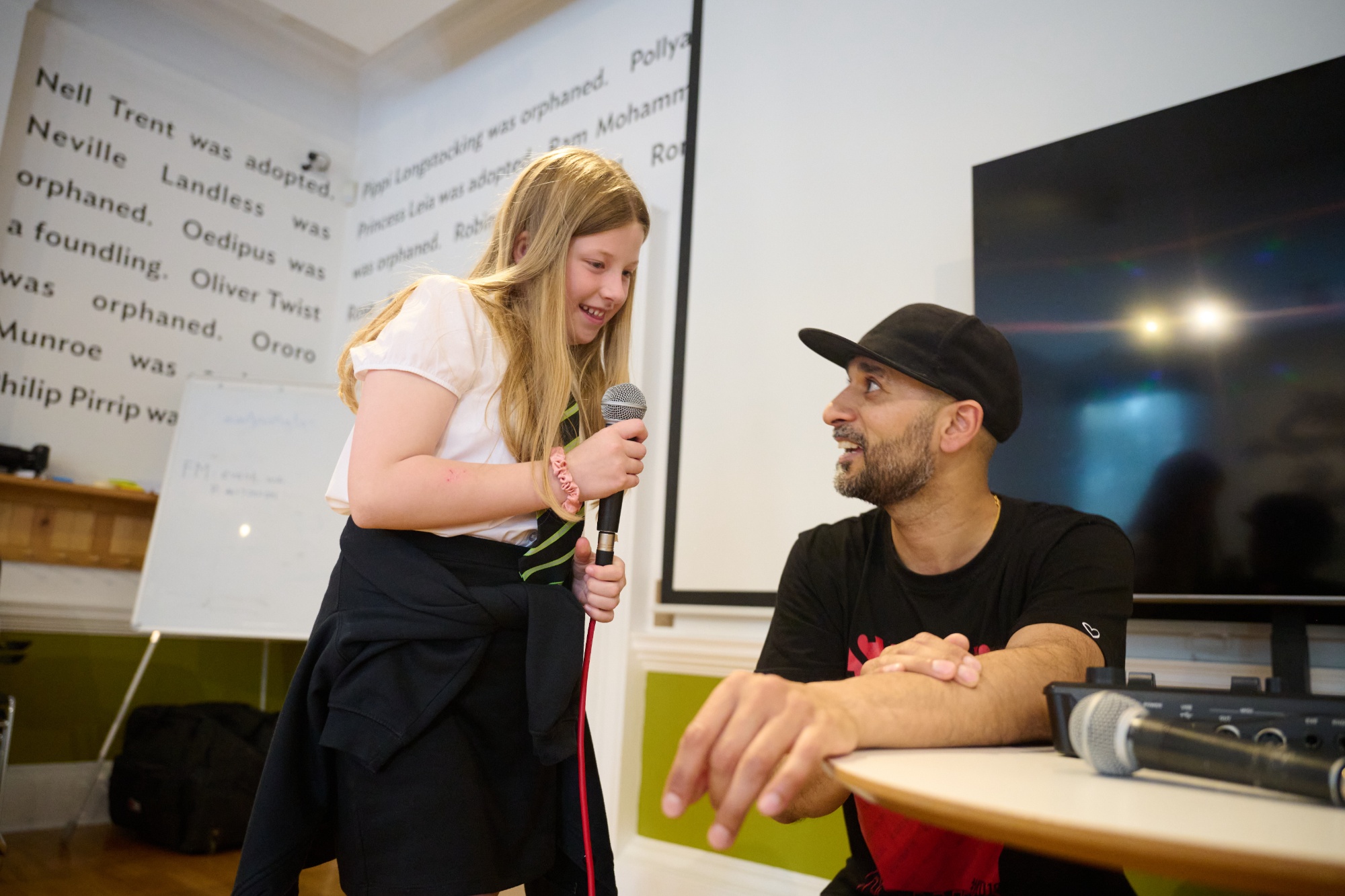 A young child holds a microphone as beatboxer Danny helps her record sounds